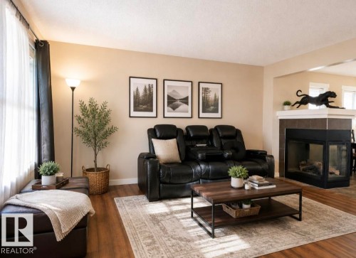 Living area featuring wood-finish flooring, a built-in fireplace with a tiled surround, and neutral wall tones - 5135 1A Avenue Sw, Edmonton, AB - Indoor Photo Showing Living Room With Fireplace