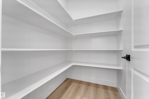 Built-in shelving, wood-finish flooring, and a contemporary matte black door handle - 82 Patriot Way, Spruce Grove, AB - Indoor With Storage
