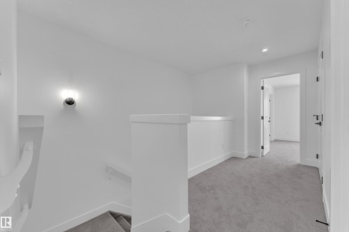 Carpeted hallway and staircase with white walls, recessed ceiling lighting, and a modern wall sconce - 82 Patriot Way, Spruce Grove, AB - Indoor Photo Showing Other Room