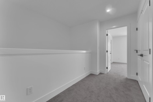 Carpeted hallway with white walls and trim, featuring a recessed ceiling light and white doors with dark hardware - 82 Patriot Way, Spruce Grove, AB - Indoor Photo Showing Other Room