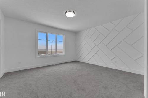 Geometric wall accent, large window, flush mount ceiling fixture, and carpet flooring - 82 Patriot Way, Spruce Grove, AB - Indoor Photo Showing Other Room