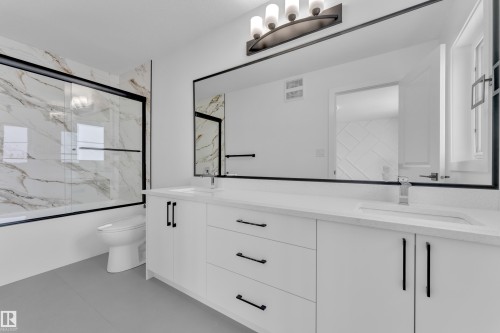 Dual-sink vanity with white cabinetry and matte black hardware, under-mount sinks, and a large framed mirror - 82 Patriot Way, Spruce Grove, AB - Indoor Photo Showing Bathroom