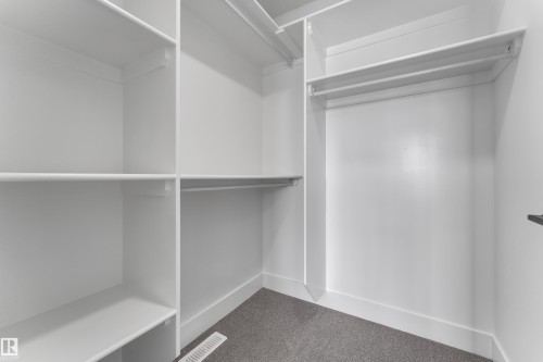 Built-in shelving, integrated hanging rods, and gray carpeted flooring - 82 Patriot Way, Spruce Grove, AB - Indoor With Storage