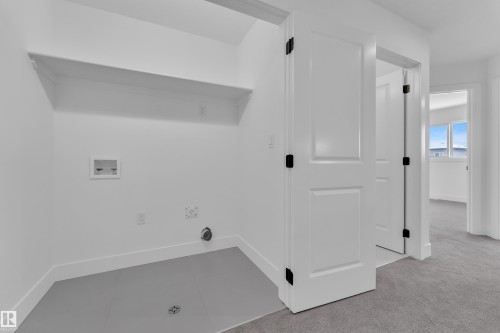 Laundry area with a built-in shelf, grey flooring, and white walls - 82 Patriot Way, Spruce Grove, AB - Indoor Photo Showing Other Room