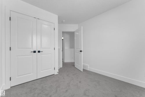 Light gray carpeting paired with white walls, white trim, and white doors featuring dark hardware - 82 Patriot Way, Spruce Grove, AB - Indoor Photo Showing Other Room