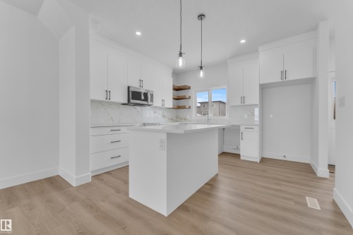 White cabinetry, wood-finish flooring, recessed lighting, and a kitchen island with pendant lighting - 82 Patriot Way, Spruce Grove, AB - Indoor Photo Showing Kitchen With Upgraded Kitchen