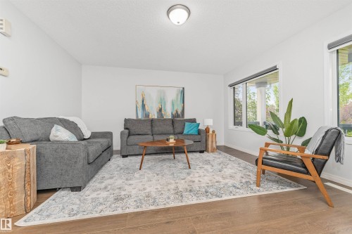 Vinyl flooring, white painted walls, and multiple windows showcasing the beautifully manicured park. - 4121 Tompkins Way Nw, Edmonton, AB - Indoor Photo Showing Living Room