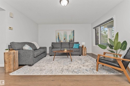 Vinyl flooring, white walls, and a prominent window showing the park out front. - 4121 Tompkins Way Nw, Edmonton, AB - Indoor Photo Showing Living Room