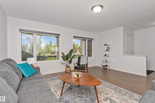 Spacious living area featuring large windows, Vinyl flooring, and white walls - 4121 Tompkins Way Nw, Edmonton, AB - Indoor Photo Showing Living Room