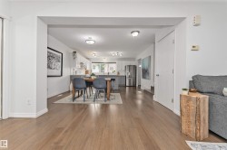 Open concept living space with wood-finish flooring, white walls, recessed lighting, and a white interior door - 