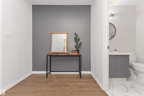 Vinyl plank flooring throughout, complemented by a gray accent wall with vertical paneling with a 2 piece bath off to the side. - 4121 Tompkins Way Nw, Edmonton, AB - Indoor Photo Showing Bathroom