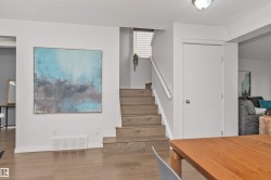 Wood-finish flooring throughout, white trim, and a staircase with a white railing - 