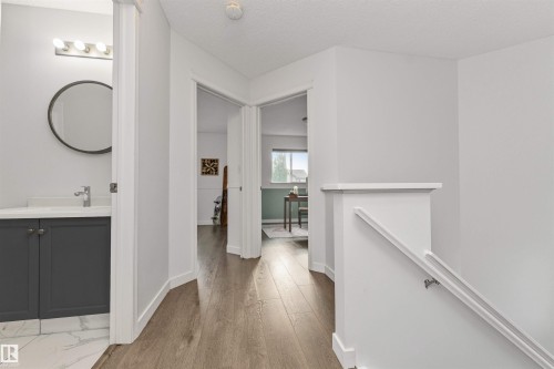 Wood-finish flooring, white walls, and a modern vanity with dark cabinetry - 4121 Tompkins Way Nw, Edmonton, AB - Indoor Photo Showing Other Room