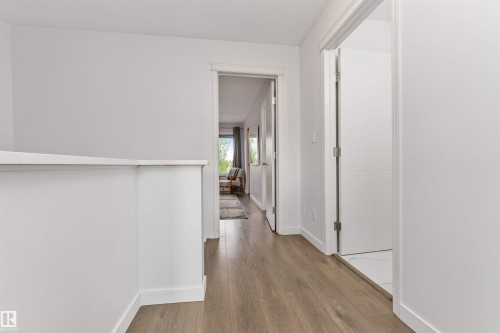 Wood-finish flooring throughout, white interior doors, and bright white walls - 4121 Tompkins Way Nw, Edmonton, AB - Indoor Photo Showing Other Room