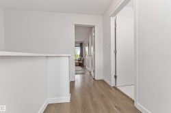 Wood-finish flooring throughout, white interior doors, and bright white walls - 