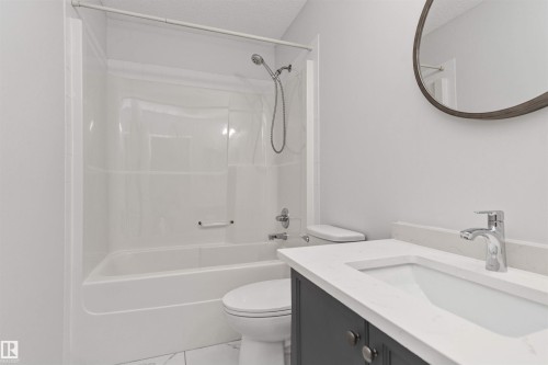 White acrylic tub and shower combination with a curved shower curtain rod - 4121 Tompkins Way Nw, Edmonton, AB - Indoor Photo Showing Bathroom