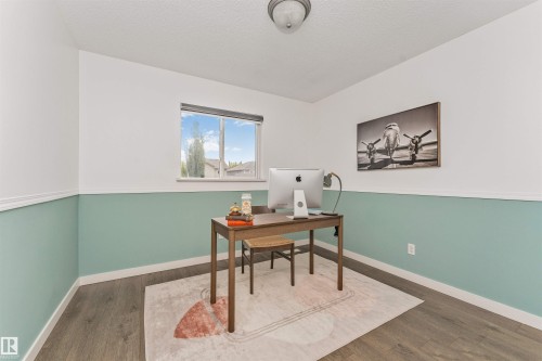 Window with a view of the yard, vinyl plank flooring, two-tone wall treatment with chair rail, and ceiling-mounted light fixture - 4121 Tompkins Way Nw, Edmonton, AB - Indoor Photo Showing Office