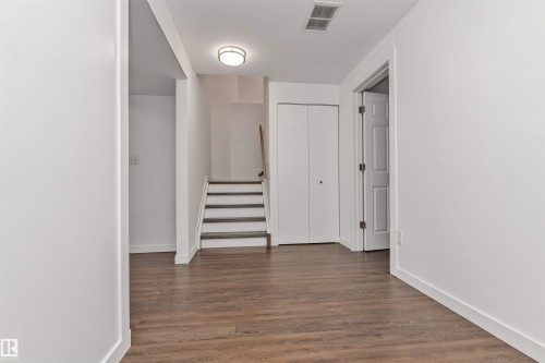 Vinyl plank flooring throughout, white walls and staircase with wood handrail - 4121 Tompkins Way Nw, Edmonton, AB - Indoor Photo Showing Other Room