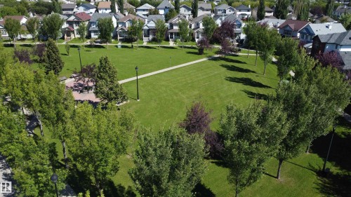 Expansive green space featuring a walking path, mature trees, and a brick-paved patio area - 4121 Tompkins Way Nw, Edmonton, AB - Outdoor With View