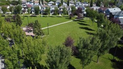 Expansive green space featuring a walking path, mature trees, and a brick-paved patio area - 