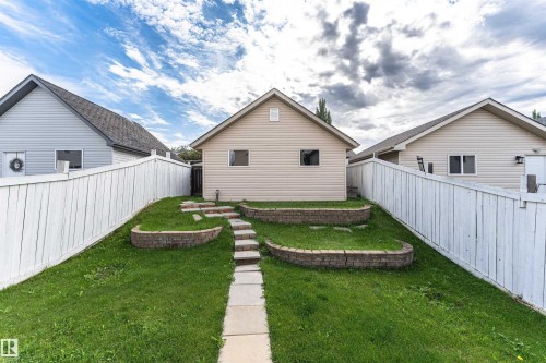 Landscaped backyard with terraced retaining walls, stone pathway, and privacy fencing - 4121 Tompkins Way Nw, Edmonton, AB - Outdoor