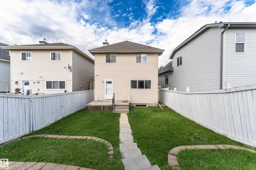 Rear exterior featuring beige siding, white trim, a gabled roof, and a privacy fence - 4121 Tompkins Way Nw, Edmonton, AB - Outdoor With Exterior