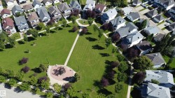 Expansive green space featuring walking paths and mature trees - 