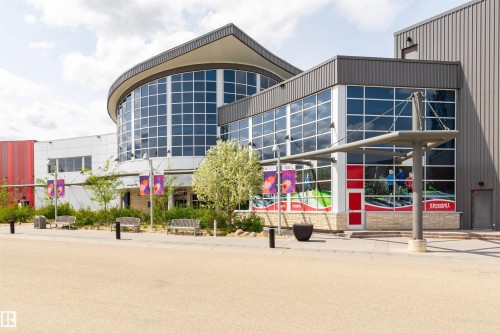 Contemporary building with extensive glass curtain walls, a curved architectural element, a metal awning, and stone base detailing - 4121 Tompkins Way Nw, Edmonton, AB - Outdoor