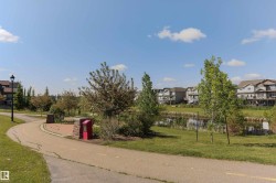 Established neighborhood featuring a paved walking path, mature trees, a tranquil pond, and residential structures with multiple balconies - 