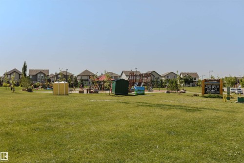 Expansive green space featuring a playground structure and surrounding residential properties - 4121 Tompkins Way Nw, Edmonton, AB - Outdoor
