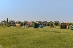 Expansive green space featuring a playground structure and surrounding residential properties - 