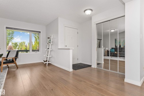 Vinyl flooring throughout, bright window with transom, white trim, mirrored closet doors, and open concept dining room - 4121 Tompkins Way Nw, Edmonton, AB - Indoor Photo Showing Other Room