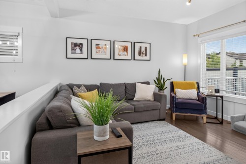 Hardwood-finish flooring featuring a contemporary area rug and white baseboards - 17305 73 Street Nw, Edmonton, AB - Indoor Photo Showing Living Room