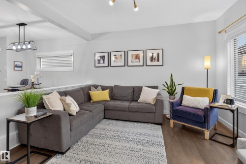 Spacious living area featuring wood-finish flooring, a contemporary light fixture, and large windows with blinds - 17305 73 Street Nw, Edmonton, AB - Indoor Photo Showing Living Room