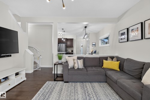Spacious living area featuring dark wood-finish flooring, light-toned walls, and an open layout to the kitchen - 17305 73 Street Nw, Edmonton, AB - Indoor Photo Showing Living Room