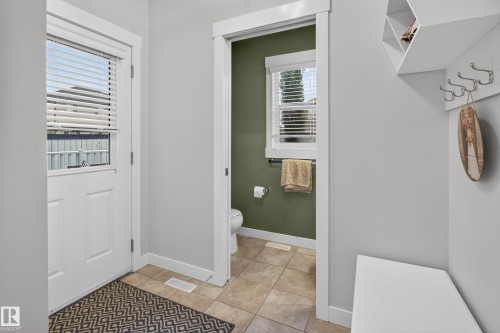 Entryway featuring a white paneled door with an integrated window and blinds, light gray wall paint, and a built-in storage bench with an overhead shelf and coat hooks - 17305 73 Street Nw, Edmonton, AB - Indoor Photo Showing Other Room