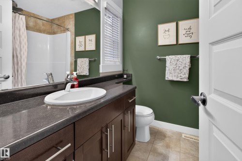 Bathroom featuring a dark wood-finish vanity with an undermount sink, dark stone-finish countertop, and chrome faucet - 17305 73 Street Nw, Edmonton, AB - Indoor Photo Showing Bathroom