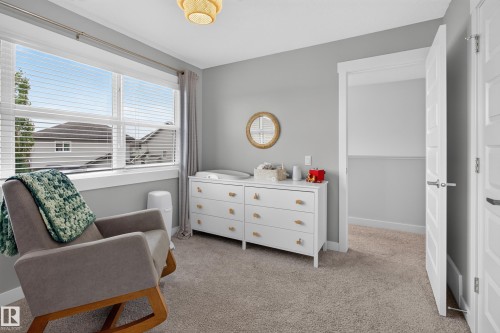 Spacious room featuring neutral carpeting, light gray wall paint, a large window with blinds, a white dresser with gold hardware, and a modern ceiling light fixture - 17305 73 Street Nw, Edmonton, AB - Indoor Photo Showing Bedroom