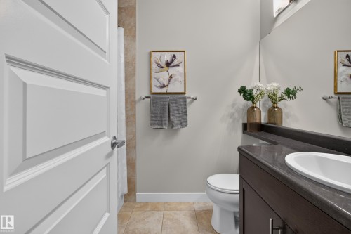 Bathroom featuring a dark wood vanity with an integrated countertop sink, wall-mounted mirror, and neutral tile flooring - 17305 73 Street Nw, Edmonton, AB - Indoor Photo Showing Bathroom