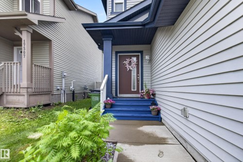 Inviting front entrance featuring a rich brown door with an upper window panel, sheltered by a contrasting dark blue portico - 17305 73 Street Nw, Edmonton, AB - Outdoor