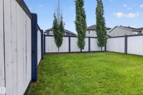 Spacious backyard featuring a lush lawn and perimeter fencing with white panels and dark posts - 17305 73 Street Nw, Edmonton, AB - Outdoor
