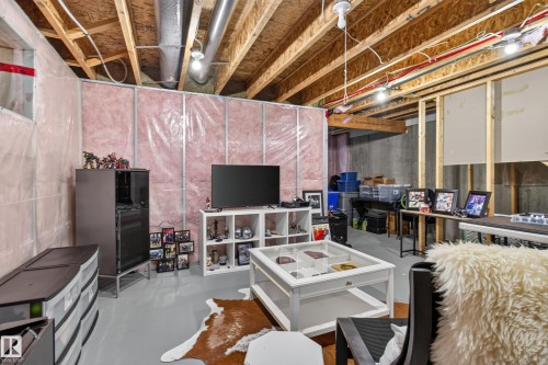 Unfinished basement featuring exposed wood joists and concrete walls, with partial pink insulation and framing - 17305 73 Street Nw, Edmonton, AB - Indoor Photo Showing Basement