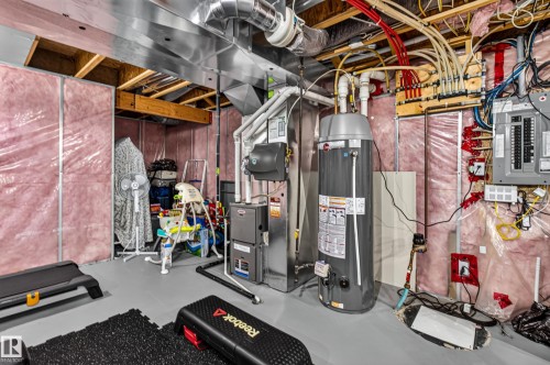 Utility room featuring a water heater, furnace, electrical panel, and exposed ceiling ductwork - 17305 73 Street Nw, Edmonton, AB - Indoor Photo Showing Basement