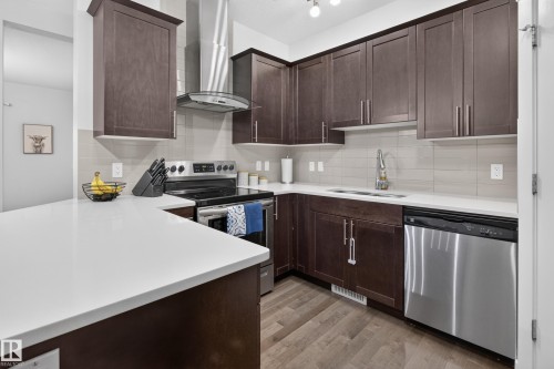 Modern kitchen featuring dark wood cabinetry, light countertops, stainless steel appliances, and a tile backsplash - 17305 73 Street Nw, Edmonton, AB - Indoor Photo Showing Kitchen With Stainless Steel Kitchen With Upgraded Kitchen