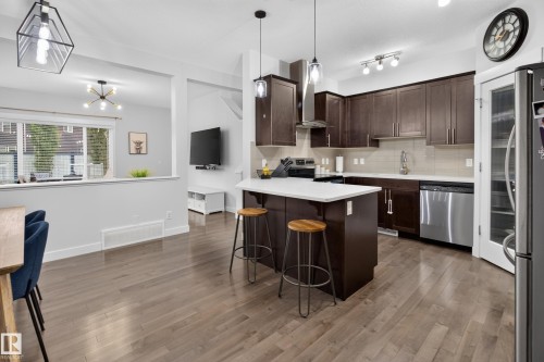 Kitchen featuring dark wood-finish cabinetry, stainless steel appliances, a white island countertop, and light wood-finish flooring - 17305 73 Street Nw, Edmonton, AB - Indoor Photo Showing Kitchen With Stainless Steel Kitchen With Upgraded Kitchen