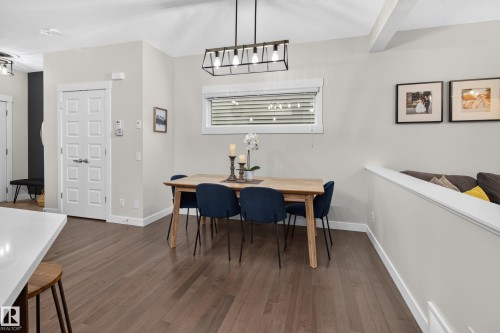 Dining area featuring wood-finish flooring and a contemporary linear chandelier - 17305 73 Street Nw, Edmonton, AB - Indoor Photo Showing Dining Room