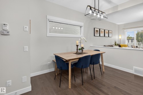 Open-concept dining area featuring wood-finish flooring and a contemporary linear chandelier - 17305 73 Street Nw, Edmonton, AB - Indoor Photo Showing Dining Room