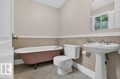 Freestanding tub, pedestal sink, tile flooring, window with natural light, and beadboard wainscoting - 9026 92 Street Nw, Edmonton, AB - Indoor Photo Showing Bathroom