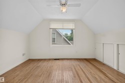 Sloped ceilings, wood-finish flooring, a ceiling fan, a window, and built-in storage - 