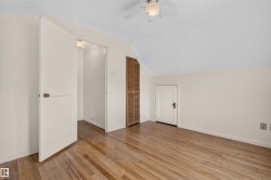 Wood-finish flooring, white walls, angled ceiling, ceiling fan with integrated lighting, and louvered closet doors - 